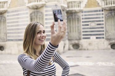 Young woman taking self portrait outside Museum of Ceramics, Valencia, Spain - CUF33995