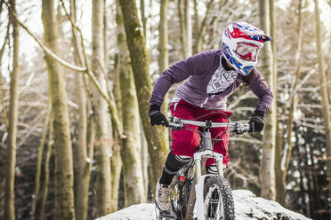 Young female mountain biker riding through forest - CUF34018
