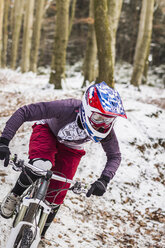Young female mountain biker riding downhill through forest - CUF34021