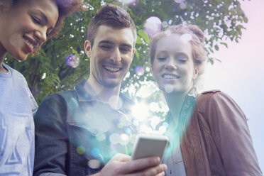 Drei Freunde schauen auf ein Smartphone mit Lichtern, die aus ihm herauskommen - CUF34026
