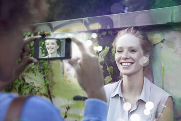 Zwei junge Frauen fotografieren mit einem Smartphone, aus dem Licht kommt - CUF34030