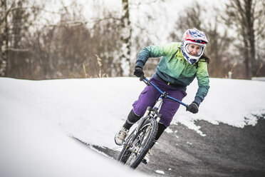 Junge Mountainbikerin fährt im Schnee - CUF34053