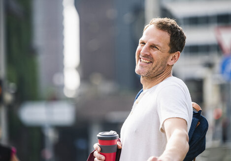 Porträt eines glücklichen Mannes mit Kaffee zum Mitnehmen in der Stadt - UUF14269