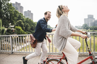 Happy couple crossing a bridge with bicycle and by foot - UUF14302