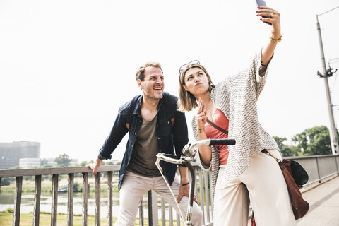 Glückliches Paar macht ein Selfie auf einer Brücke, lizenzfreies Stockfoto