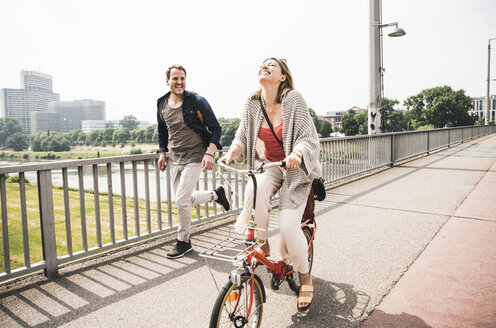 Happy couple crossing a bridge with bicycle and by foot - UUF14304