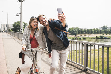 Happy couple taking a selfie on a bridge - UUF14306