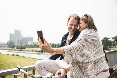 Happy couple taking a selfie on a bridge - UUF14307