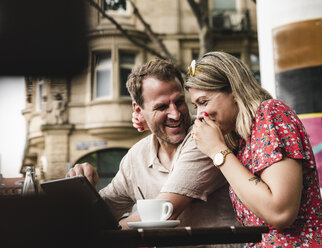 Happy couple with tablet at an outdoor cafe - UUF14309