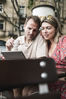 Paar schaut auf Tablet in einem Café im Freien - UUF14312