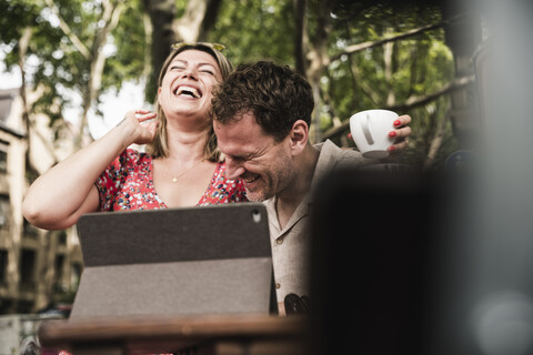 Happy couple with tablet at an outdoor cafe stock photo