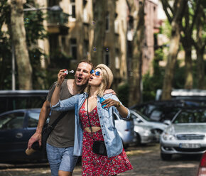 Couple blowing soap bubbles in the city together - UUF14322