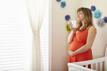 Pregnant woman drinking coffee and daydreaming in nursery - ISF14234