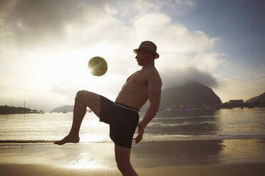 Mid adult man playing keepy uppy on Botafogo beach, Rio De Janeiro, Brazil - CUF34133