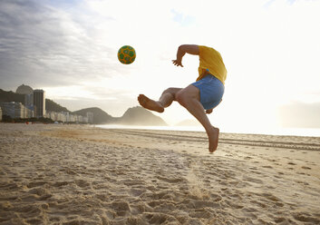 Mid adult man playing soccer on Copacabana beach, Rio De Janeiro, Brazil - CUF34149