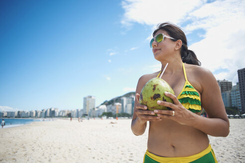 Ältere Frau trinkt aus einer Kokosnuss am Strand der Copacabana, Rio De Janeiro, Brasilien - CUF34151