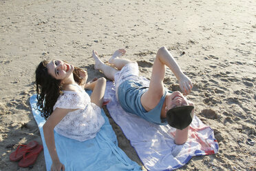 Porträt eines jungen Paares auf Handtüchern am Strand, Blick nach oben - CUF34203
