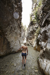 Young woman paddling in stream between rock formation, Costa del Sol, Spain - CUF34217