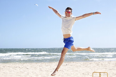 Junger Mann springt mitten in der Luft am Strand, Port Melbourne, Melbourne, Australien - CUF34220