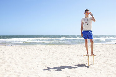 Junger Mann posiert auf einem Hocker am Strand, Port Melbourne, Melbourne, Australien - CUF34221