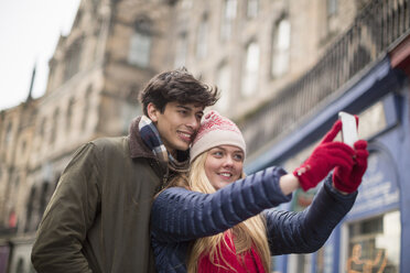 A young couple photograph themselves in the Grassmarket in Edinburgh, Scotland - CUF34228