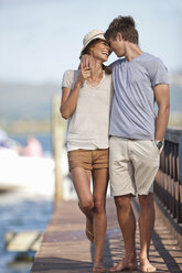 Young couple walking along jetty, arms around each other - CUF34243