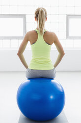 Junge Frau sitzt auf einem Gymnastikball, Rückansicht - CUF34277