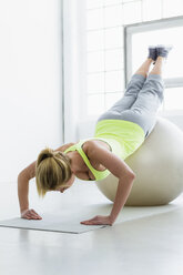 Junge Frau beim Liegestütz mit Gymnastikball - CUF34284