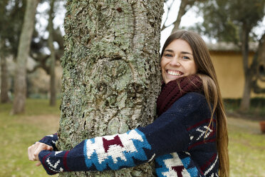 Young woman hugging tree in forest - CUF34357