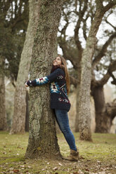 Junge Frau umarmt Baum im Wald - CUF34358