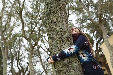 Junge Frau umarmt Baum im Wald - CUF34359