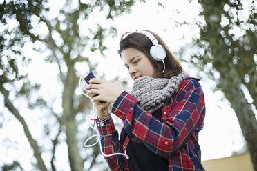 Teenage girl using mp3 in forest - CUF34362