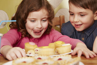 Girl staring at plate full of cakes, licking lips - CUF34396