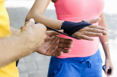 Personal trainer wrapping bandages around female boxers hand - CUF34420