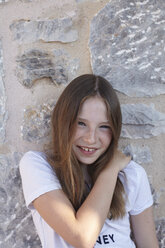 Portrait of shy smiling girl leaning against wall - CUF34422