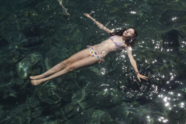 Mädchen schwimmt mit geschlossenen Augen im Meer - CUF34423