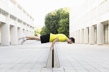 Young man balancing horizontally on divider - CUF34430