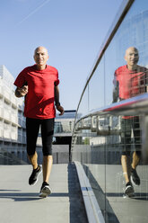 Läufer entlang einer Glasbalustrade, München, Deutschland - CUF34444