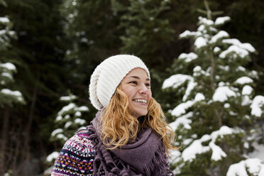 Portrait of laughing young woman in front of snow covered fir trees - ISF14307