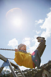 Young boy swinging high on playground swing - ISF14319