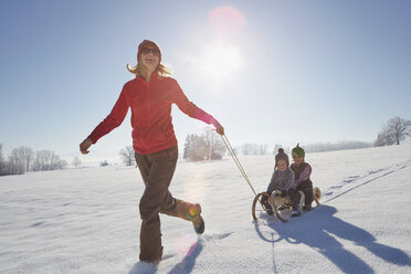 Mother pulling sons along on sled - ISF14324