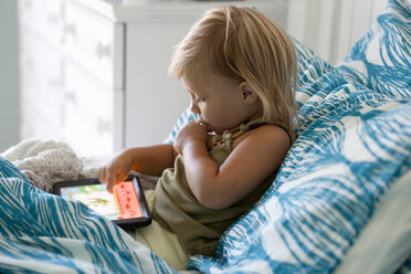 Weibliches Kleinkind im Bett sitzend mit digitalem Tablet - ISF14374