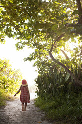 Rückansicht eines barfuß gehenden Mädchens mit Sonnenhut auf einem bewaldeten Strandweg, Anna Maria Island, Florida, USA - ISF14386