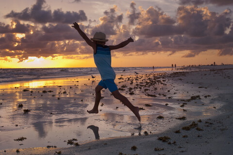 Junge auf Erkundungstour am Strand bei Sonnenuntergang, lizenzfreies Stockfoto