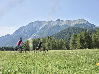 Austria, Tyrol, Mieming, couple riding bike in alpine scenery - CVF00859