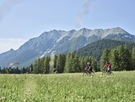 Österreich, Tirol, Mieming, Paar fährt Fahrrad in alpiner Landschaft - CVF00860