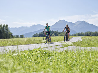 Österreich, Tirol, Mieming, Paar fährt Fahrrad in alpiner Landschaft - CVF00862