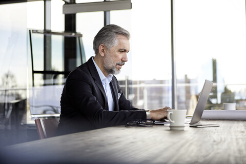 Geschäftsmann mit Laptop am Schreibtisch im Büro, lizenzfreies Stockfoto