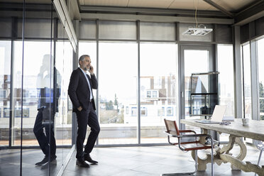 Geschäftsmann steht im Büro und spricht mit seinem Handy - RBF06312