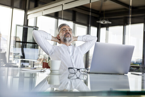 Businessman at desk in office leaning back stock photo